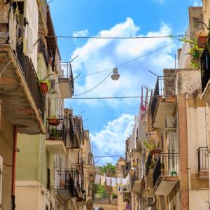 Rue étroite avec balcons et linge séchant au soleil.