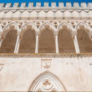 Façade gothique avec arcs et créneaux sous ciel bleu.