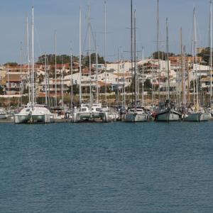 Voiliers amarrés dans un port avec des maisons en arrière-plan.