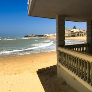 Plage de sable avec maisons et mer calme sous ciel bleu.