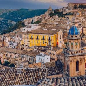 Vue de Ragusa Ibla avec bâtiments historiques et paysage vallonné.